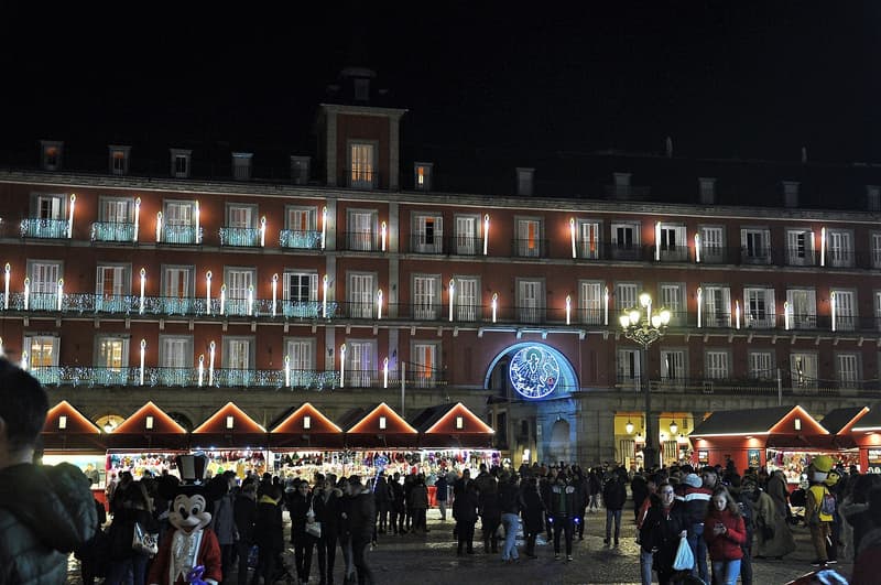 The Plaza Mayor in Madrid on a December night, lit for Christmas above a row of red market stalls