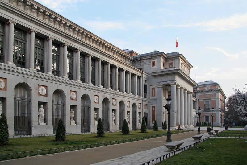 The west front of the Museo del Prado in Madrid, a long neoclassical facade of Ionic columns and arched niches holding statues